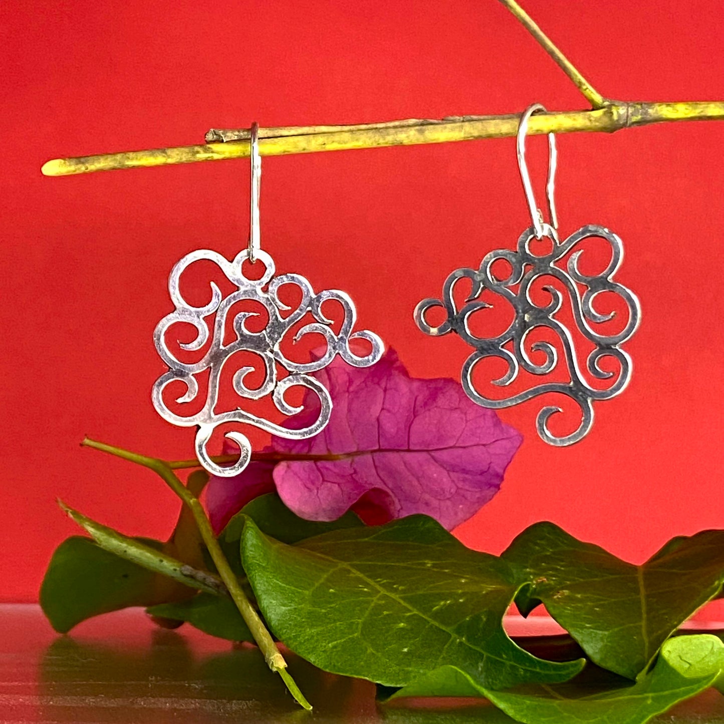 Aretes de Plata Fina 950 con Inspiración en la Naturaleza. Composición artística con ramita de buganvilla violeta y fondo rojo intenso (Buenaventura).