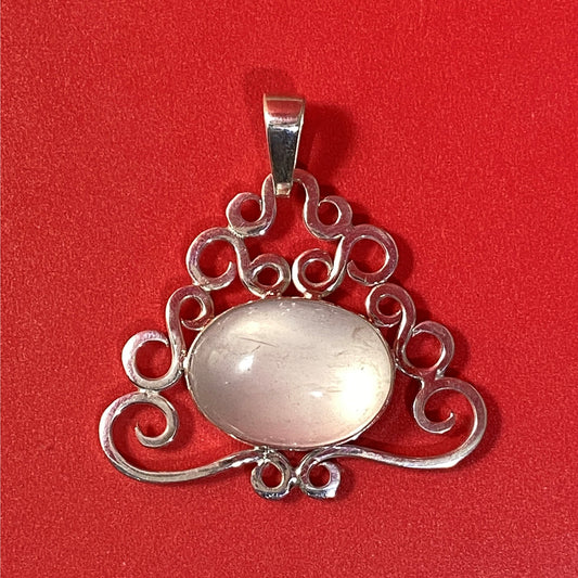 Dije de Cuarzo Rosado en Plata Fina 950. Joyas de Tendencia con marco de volutas sobre fondo rojo sólido (Cúcuta).